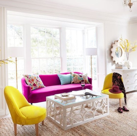 a chic neutral living room in modern farmhouse style, with a magenta sofa, sunny yellow chairs, a glass table and colorful pillows