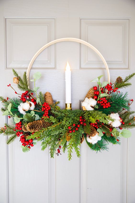 an embroidery hoop Christmas wreath with evergreens, pinecones, cotton, berries, a candle in the center is a bold idea