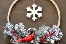 25 an embroidery hoop Christmas wreath with snowy evergreens, berries, snowy pinecones and a red bird plus a large snowflake