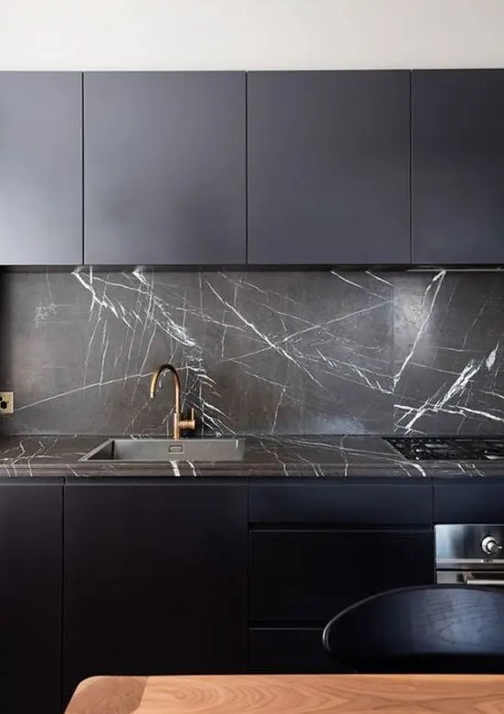 navy minimalist cabinets plus a black marble backsplash and countertops that spruce up the whole space and make a statement