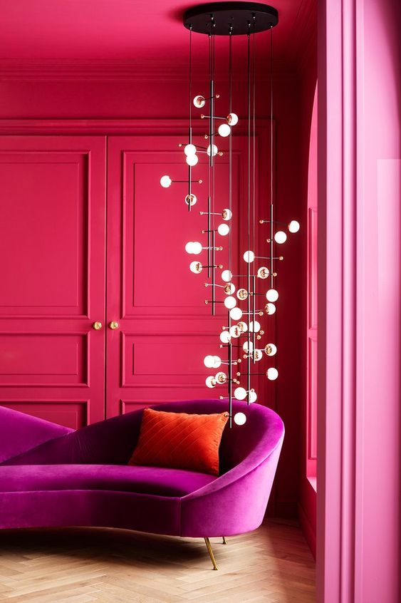 a hot pink living room with molding, a magenta loveseat, a catchy pendant lamp is jaw-dropping