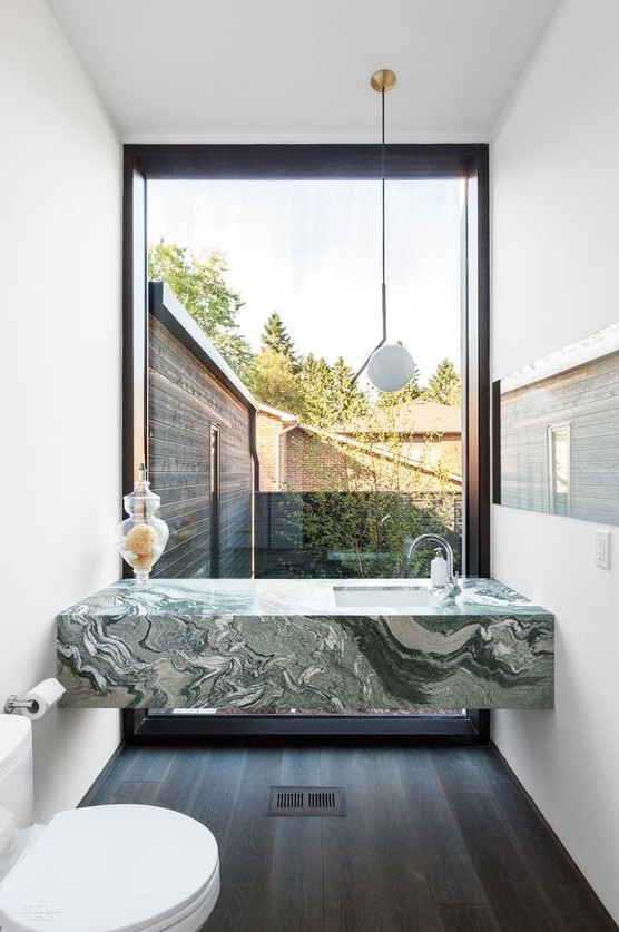 a green marble modern vanity in a small powder room with a view to the courtyard