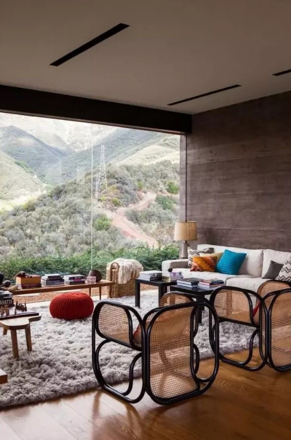 a beautiful modern living room with a panoramic view, with chic furniture and lovely black cane chairs, lots of books and colorful pillows