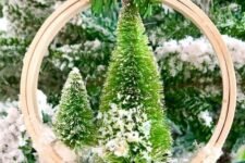 32 a pretty embroidery hoop Christmas ornament with bottle brush trees, a berry, faux snow and a plaid ribbon on top