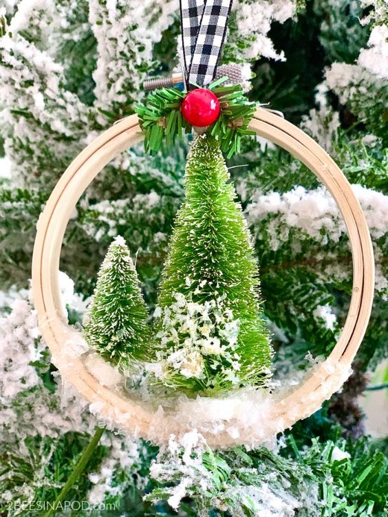 a pretty embroidery hoop Christmas ornament with bottle brush trees, a berry, faux snow and a plaid ribbon on top