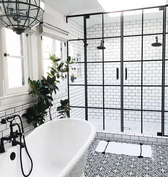 a freestanding tub is connected to the shower with a black faucet and a black glass pendant lamp over it
