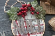 33 a pretty embroidery hoop Christmas ornament with red and white plaid fabric, glitter letters, snowy leaves and berries for rustic Christmas decor