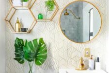 35 a cool bathroom with printed wallpaper, gold hexagon shelves, a round mirror in a gold frame, gold fixtures and handles is very bold
