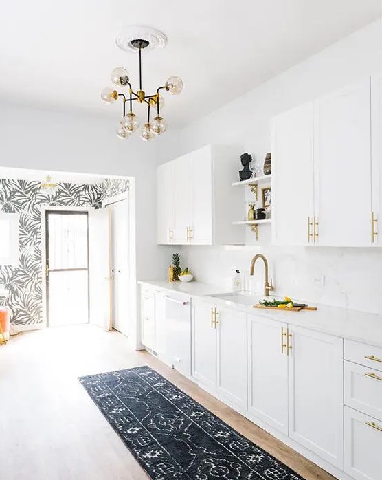 a mid-century modern kitchen done in white, with brass handles and faucets