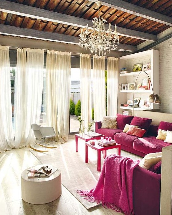 a refined neutral living room with built-in shelves, two magenta sofas, neutral furniture and textiles plus a crystal chandelier