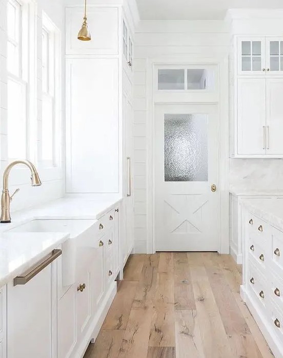 a vintage white kitchen with brass handles and wooden floors that make it cozier