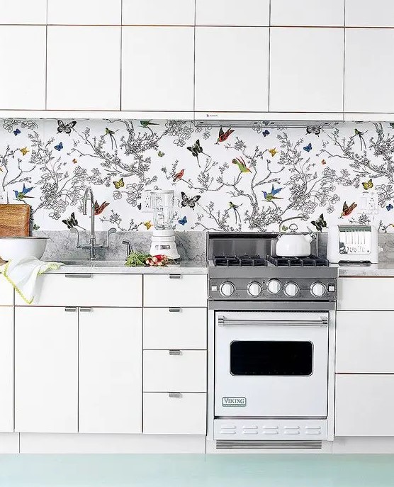 to avoid a boring look in an all-white kitchen, rock a colorful wallpaper backsplash with butterflies and birds