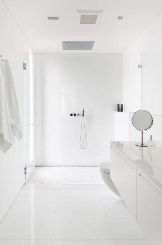 a minimalist white bathroom with a window in the shower space, simple large scale tiles and a floating sleek vanity