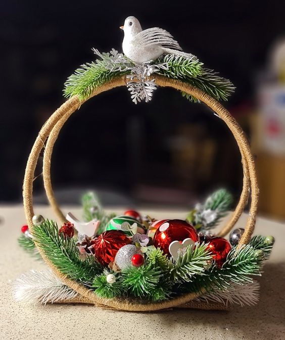 a cool Christmas decoration of two embroidery hoops, evergreens, red and silver ornaments and a bird on top is a lovely idea