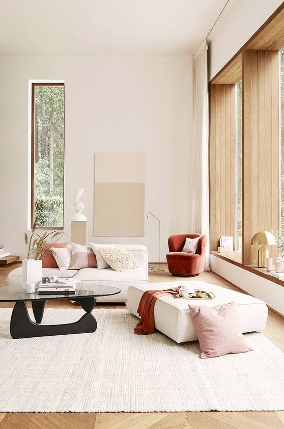 a minimalist neutral living room done with chic furniture, a terracotta chair, blankets and pillows for a touch of color