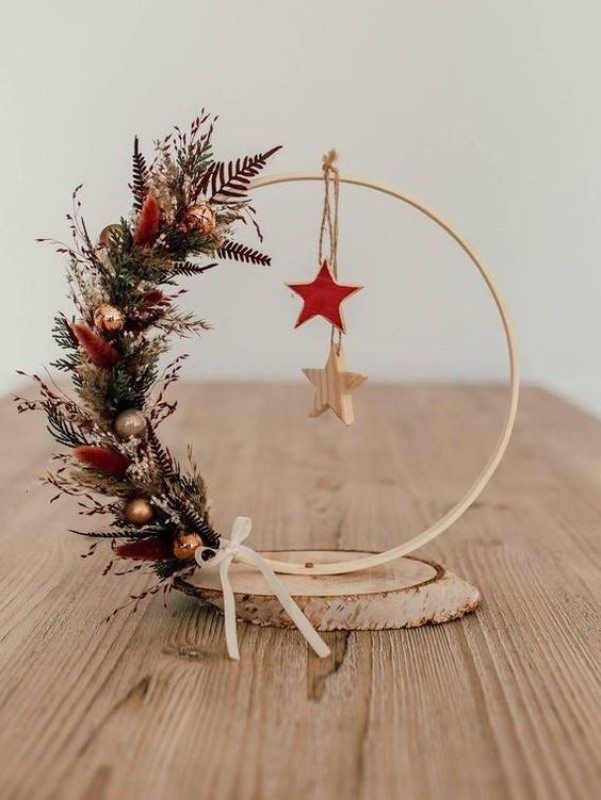 a stylish Christmas embroidery hoop decoration with greenery, dried grasses, small ornaments, a couple of wooden stars