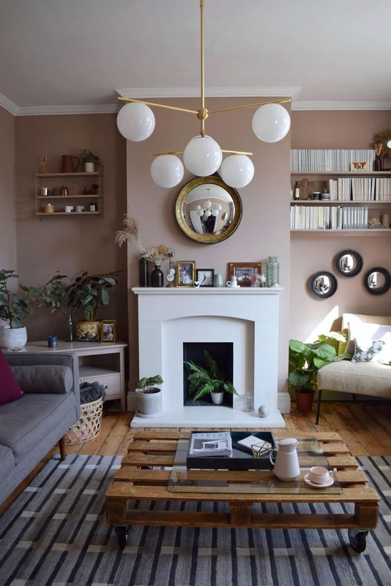 a welcoming mid-century modern living room with tan walls, a non-working fireplace, some comfy seating furniture and a pallet coffee table