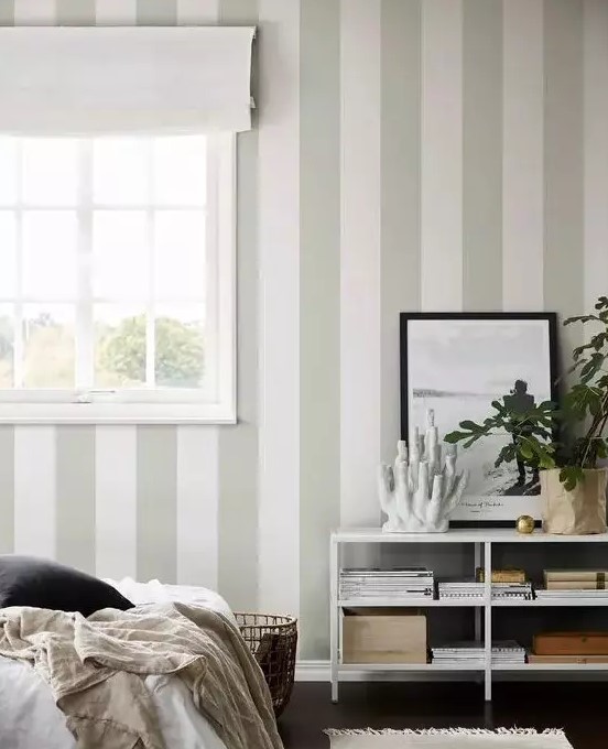 a neutral and ethereal bedroom with a green and white striped wall, neutral textiles and potted plants is very beautiful