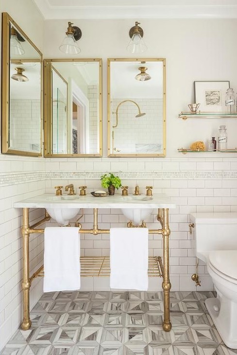 a chic bathroom with a retro touch, with gold framed mirrors, a gold vanity stand and gold shelves plus a mosaic floor