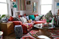 56 a super colorful and bold boho living room with bright layered rugs, a red sofa with colorful pillows and a bold gallery wall