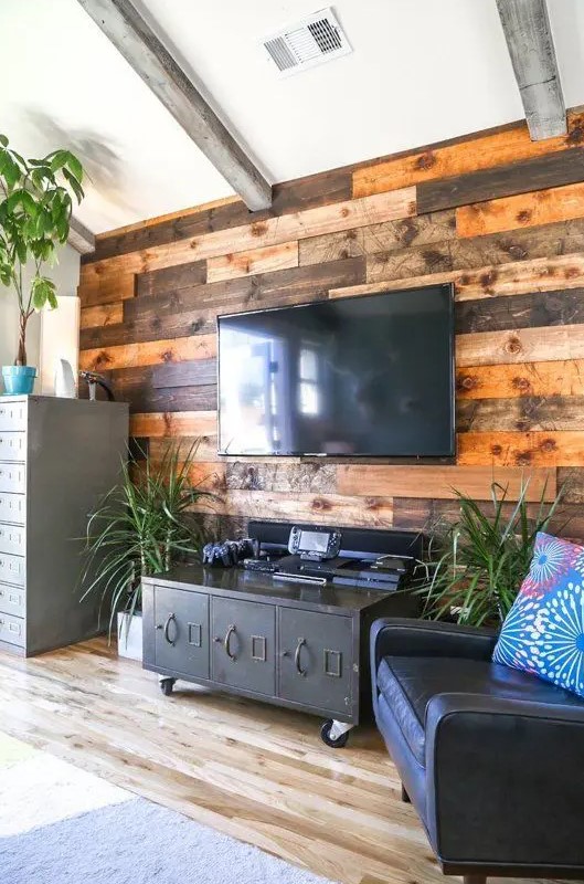 a weathered and stained wood accent wall softens the industrial-inspired living room with vintage touches