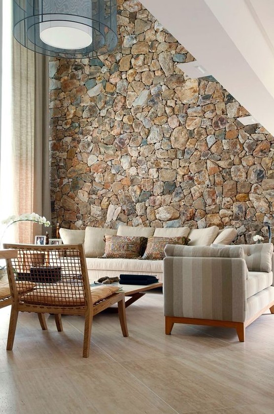a rough stone accent wall adds a natural feel to the contemporary living room and brings a touch of natural color