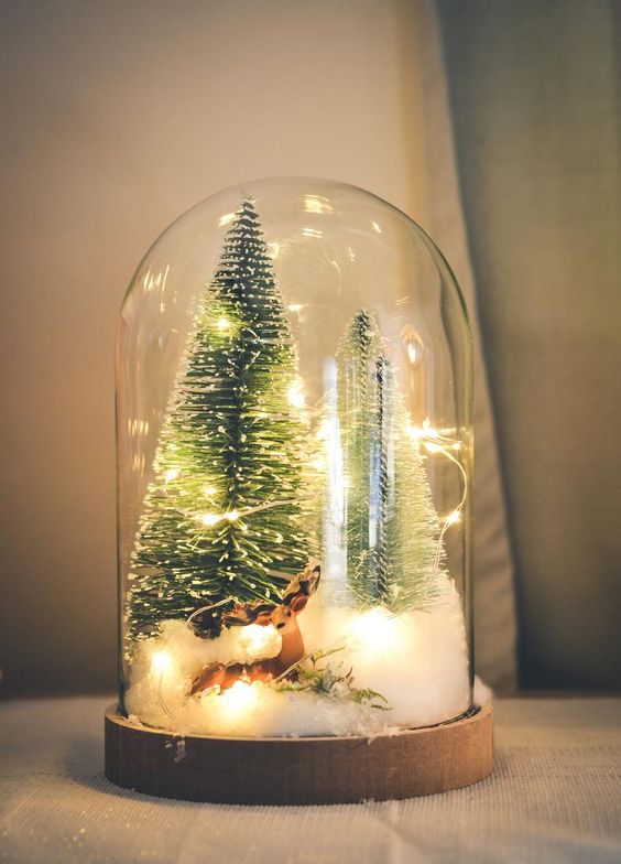 a Christmas terrarium with faux snow, a deer, lights, bottle brush trees is a lovely idea for the holidays