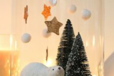 a Christmas terrarium with faux snow, a polar bear, bottle brush Christmas trees, pompoms and glitter stars