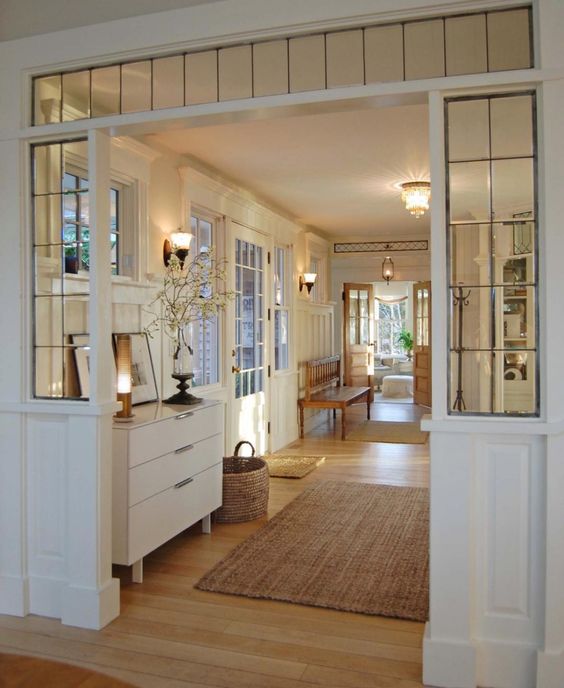 a beautiful vintage-inspired white entryway with elegant furniture, a transom window and some sidelights