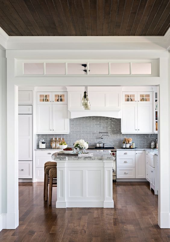 a beautiful white vintage kitchen with no door and a transom window over the entry to let more natural light inside
