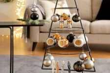 a black metal frame Christmas tree with white, silver, black and orange ornaments hanging on it is all cool