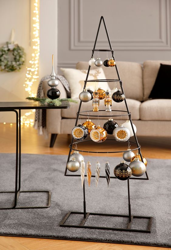a black metal frame Christmas tree with white, silver, black and orange ornaments hanging on it is all cool