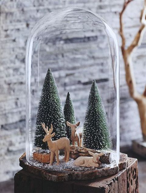 a cloche Christmas terrarium with bottle brush Christmas trees, some logs and deer figurines is ultimately cute