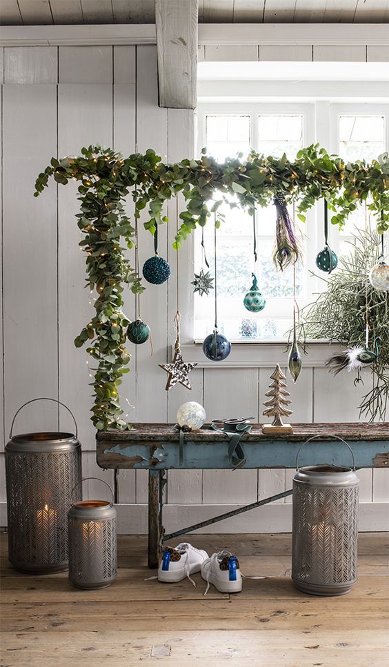 a cool Christmas ornament display covered with greenery and lights and with various green and blue ornaments is a lovely idea