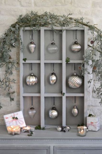 a cool grey Christmas ornament display with mercury glass ornaments and greenery on top is pure elegance