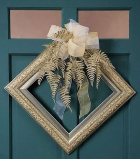 a decorative gold frame Christmas wreath with gilded leaves and a large ribbon bow on top is a fantastic idea for a glam space