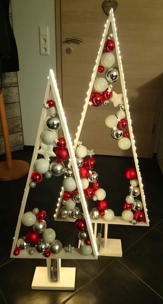 a duo of lit up frame Christmas trees with white, silver and red ornaments and some stars inside is amazing