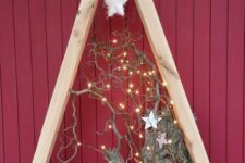 a frame Christmas tree with evergreens, stars, branches and lights is a pretty outdoor holiday decoration