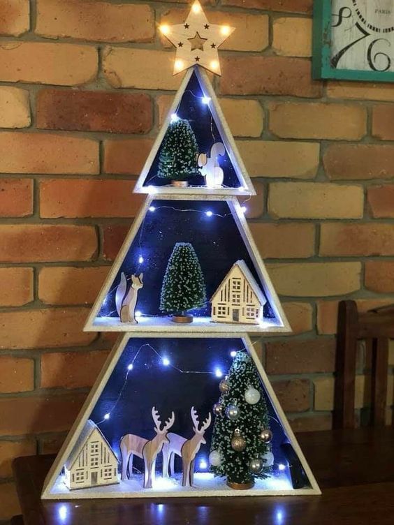 a frame Christmas tree with snowy scenes inside, with lights, trees and some houes and animals is a unique decor idea