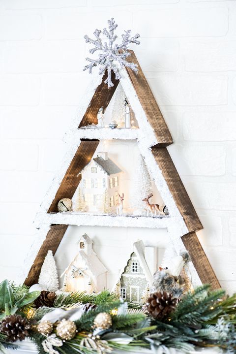 a frame Christmas tree with some houses, trees and animals inside, topped with a silver snowflake looks amazing