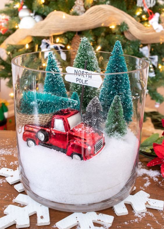 a fun Christmas terrarium in a large jar, with faux snow, a red van, some bottle brush Christmas trees