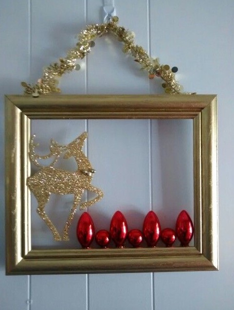 a glam frame Christmas wreath in gold, with red ornaments, a gold glitter reindeer and a gilded garland is amazing