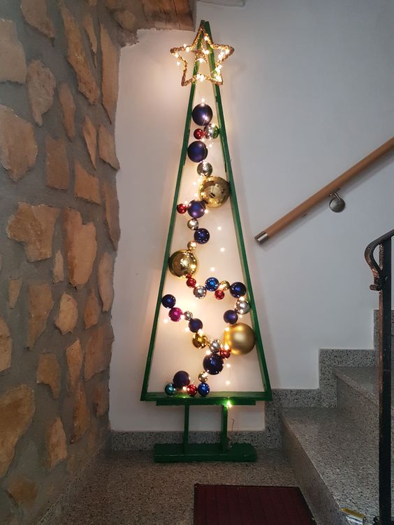 a green metal Christmas tree with lights and colorful ornaments plus a large lit up star on top is amazing for home decor