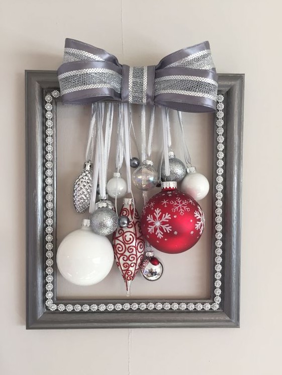 a grey frame Christmas wreath with white, silver and red ornaments and a large silver bow on top
