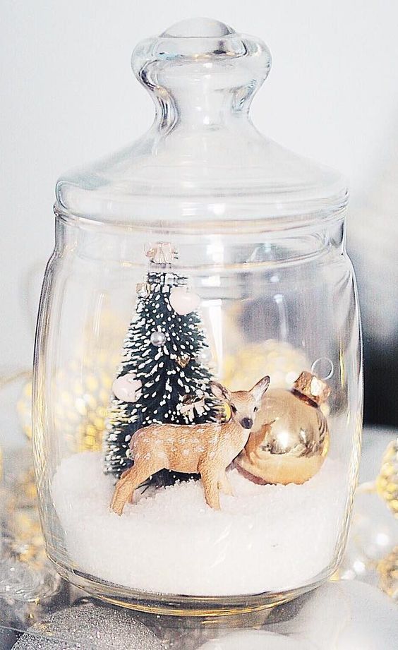 a jar with faux snow, a deer, a Christmas tree and a large ornament is a great example of a Christmas terrarium