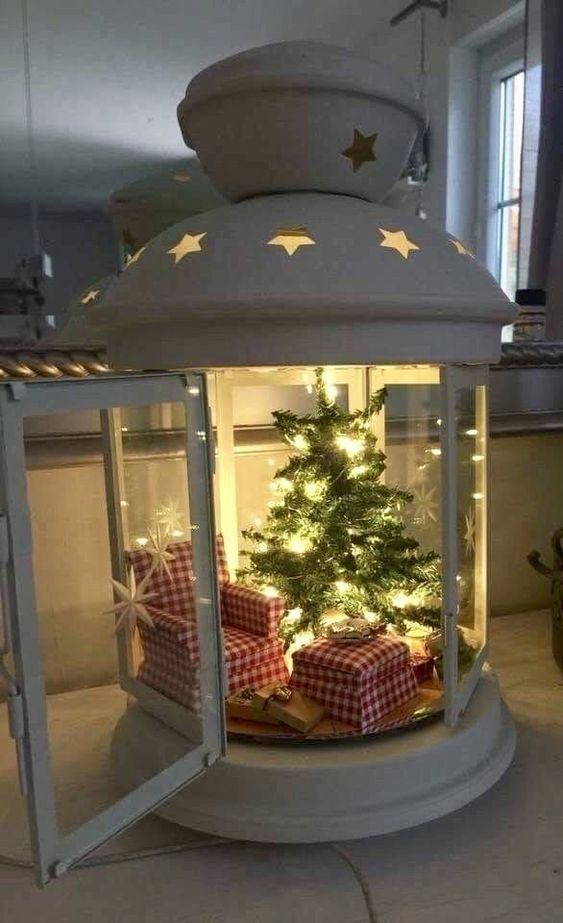a lantern terrarium with a red chair and a footrest, a Christmas tree with lights is a stylish and cozy idea