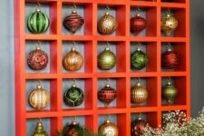 a large Christmas ornament display with lots of beautiful vintage ornaments and evergreens on top