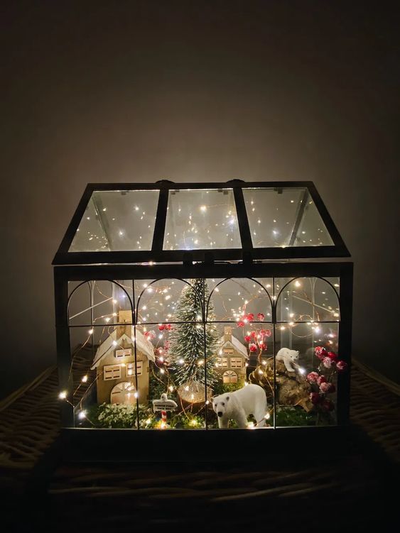 a large Christmas terrarium with moss, lights, mini houses, some polar bears and berries plus a bottle brush Christmas tree