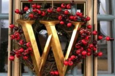 a lovely frame Christmas wreath with a vintage wreath with berries and a large gold monogram looks super chic