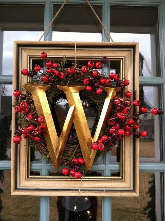 a lovely frame Christmas wreath with a vintage wreath with berries and a large gold monogram looks super chic